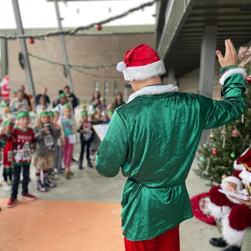Kids at Elf Academy raise hands to pledge with head elf