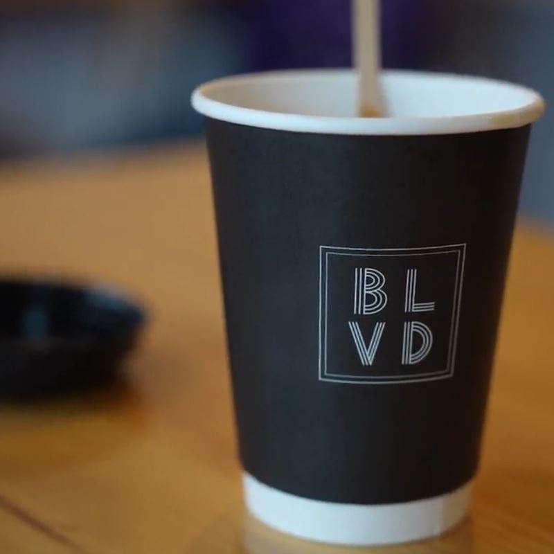 Boulevard West coffee cup with stirring stick on table