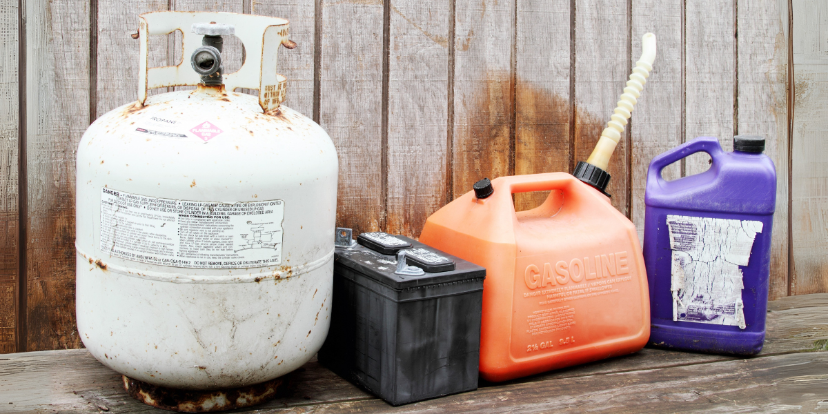 Hazardous waste items, including a propane tank, car battery, gasoline, and chemical container