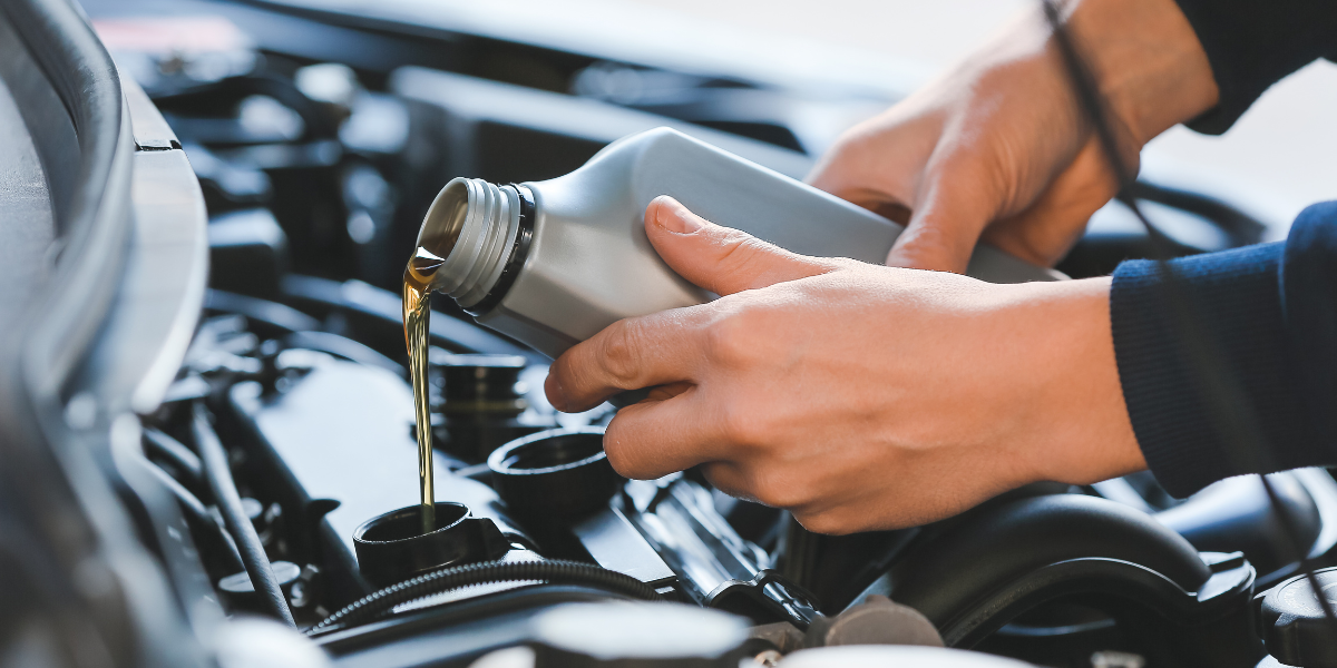 person pouring motor oil into a car engine
