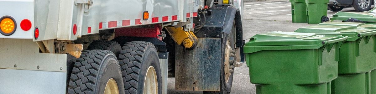 Garbage truck in street with trash bins
